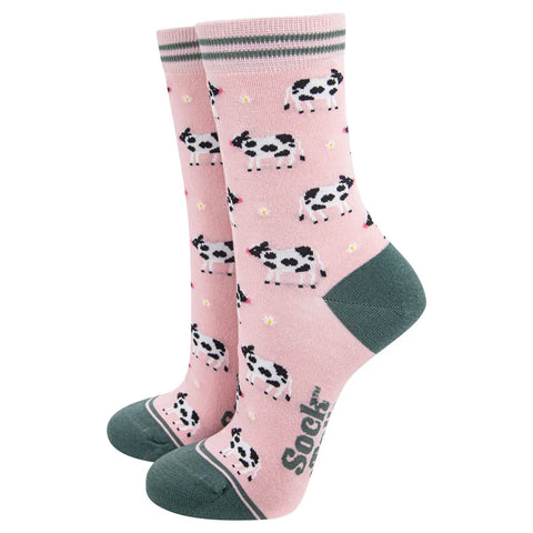 Pink socks with cow pattern and green accents on a white background
